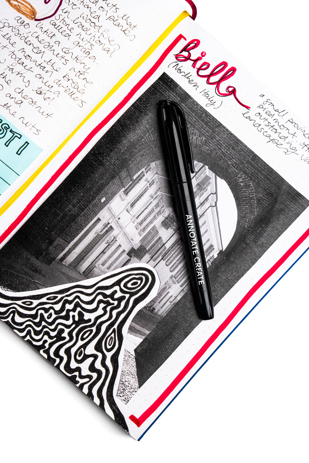 Nōto whiteboard marker resting on an open notebook page with handwritten notes and a printed architectural photo