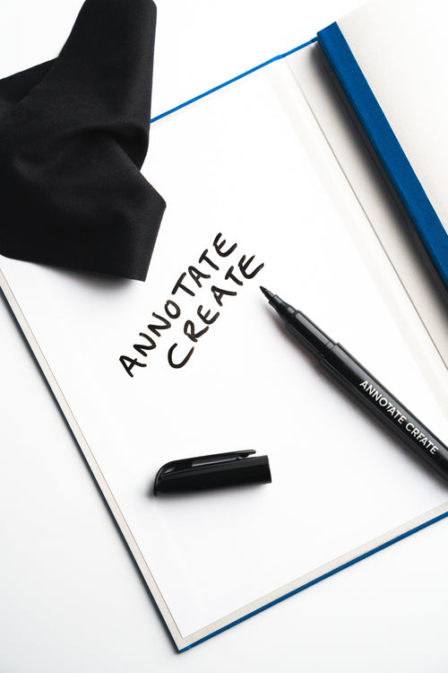 Whiteboard marker resting on Nōto notebook's built-in whiteboard page with black cloth pouch